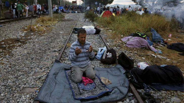 A Syrian refugee prays on a rail track at the Greek-Macedonian border. Photo: Yannis Behrakis