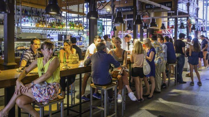 Crowds of tourists and locals enjoying drinks and tapas under the cast iron vault of the Mercado de San Miguel, the iconic market in the heart of Madrid.  Photo: iStock