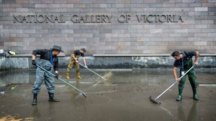 Cleaners work on the moat at the NGV. The collected coins are recorded as NGV donations and will go towards the acquisition of art. Photo: Penny Stephens