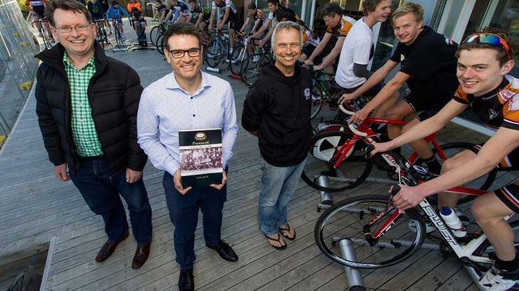 Author and club historian Ben Schofield, president Ag Giramondo, holding the book, and roller coach Cameron McFarlane at the Brunswick Velodrome with cyclists. Photo: Paul Jeffers