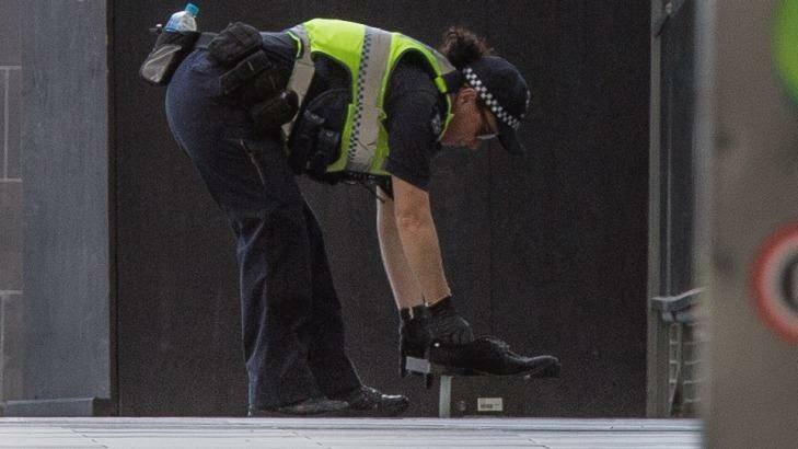 A police officer removes the 'suspicious' shoes. Photo: Jason South