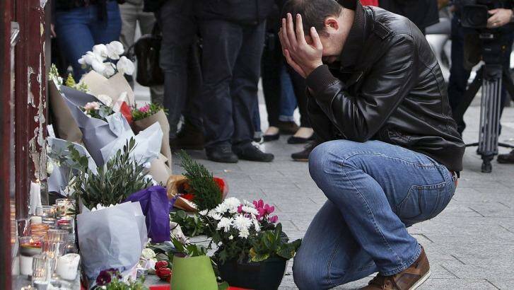 Grief stricken: A man lays flowers at the scene of one of the attacks, in front of the Carillon cafe, in Paris.  Photo: Thibault Camus