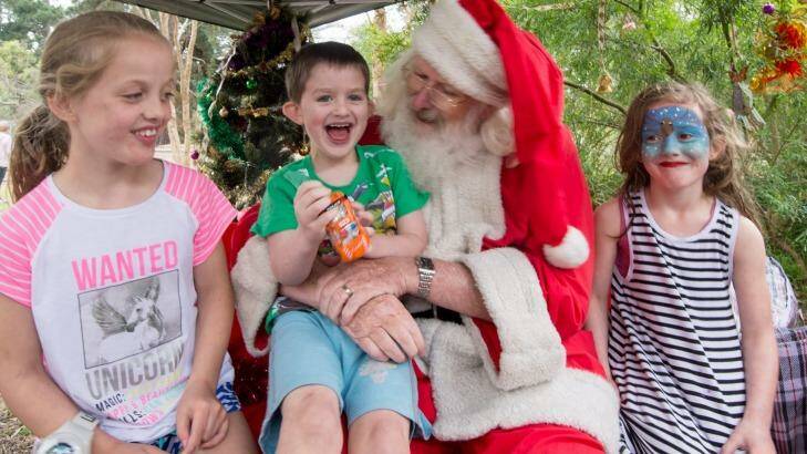 Stephen Fox charms Paige, 8, Hunter, 4, and Indi, 6, at the Kalparrin centre's Christmas party. Photo: Penny Stephens