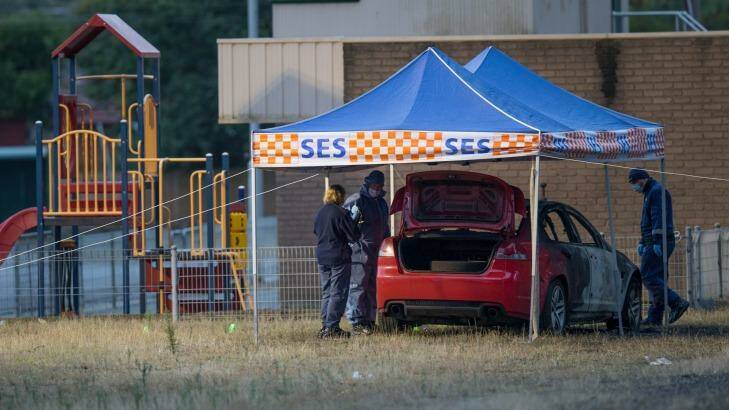 Forensics police inspect the burnt out car. Photo: Jason South