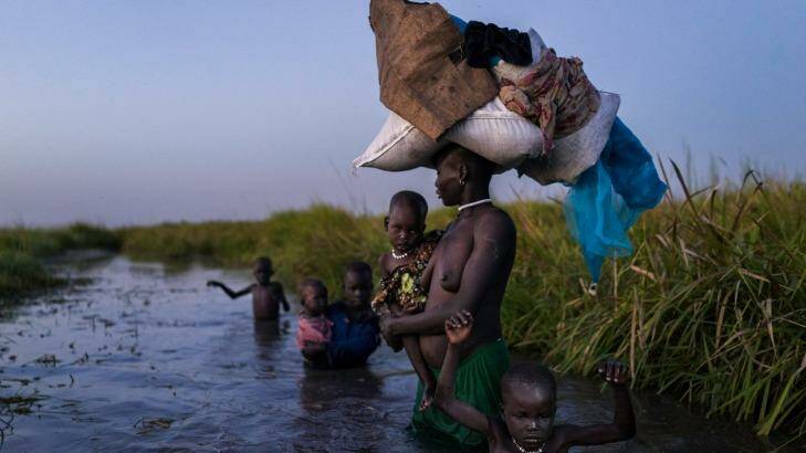 Showing at the festival: A woman with her five children walks back through cold swamps at dusk to her hiding place after receiving food. Kok Island, South Sudan, 2015.  Photo: Fondation Ortiz