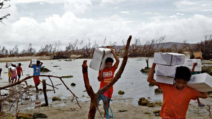 Locals carry aid packages after Cyclone Haiyan. Photo: Brendon Esposito