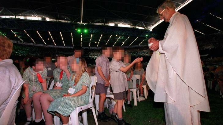 Father Joseph Doyle administers Mass to school children in 2000 at a huge celebration at the Docklands stadium in Melbourne. Photo: Simon Schluter