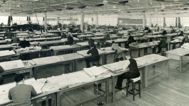 Draftsmen bending over desks in a large warehouse in Fishermans Bend. A banner at the front of the large room provides cheerful motivation: "Victory begins on the drawing board!" it reads. Photo: Defence Science and Technology G