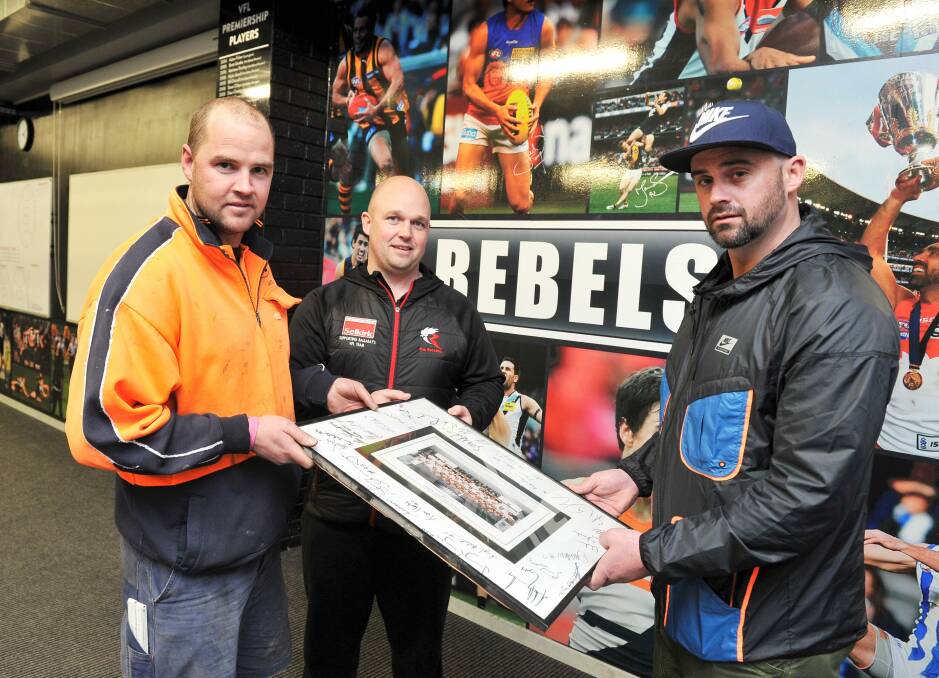 PROUD ACHIEVEMENT: Former Rebels players Jaye Cahir, Marc Greig and Shane Fisher with a signed photo of the 1997 premiership team. Picture: Lachlan Bence