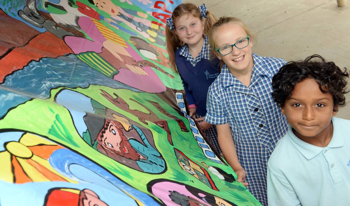 Savannah, year 6, Jane, year 6, and Thisen, year 5, with the cross-cultural mural. Picture: Kate Healy