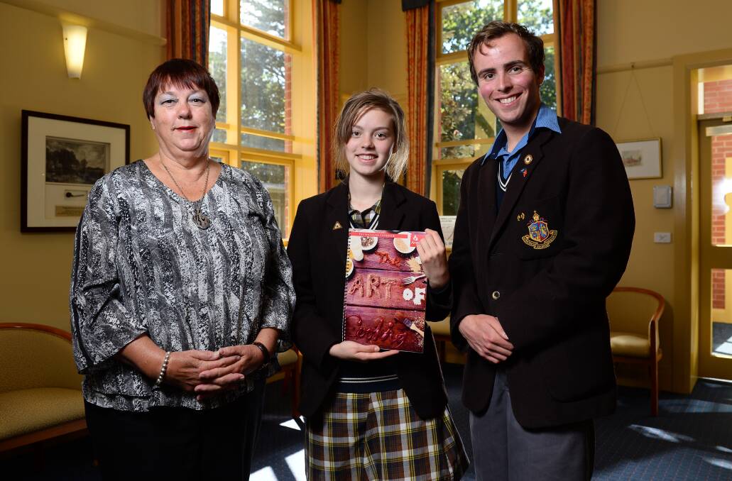Foodies for a cause: Anglicare volunteer Sue Fry and Ballarat Grammar School students Elizabeth Wilson and Matthew Hall with the new cookbook. PICTURE: ADAM TRAFFORD