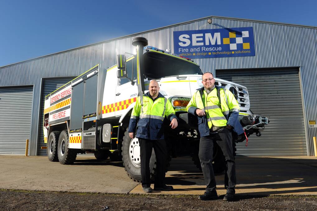 Back on a roll: Product manager Jon Julian and engineering manager Alex Heiden in front of one of the trucks to be sent to Papua New Guinea. PICTURE: JUSTIN WHITELOCK
