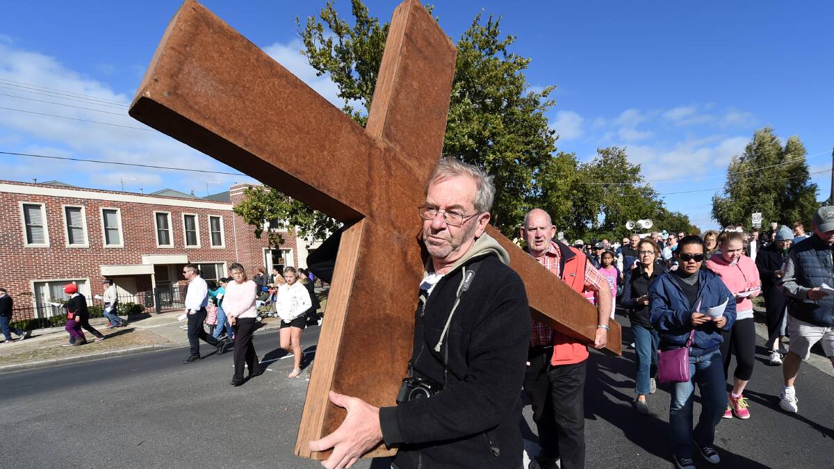 Rob Ball carries the cross during the annual Good Friday Way of the Cross walk through Ballarat streets. Picture: LACHLAN BENCE