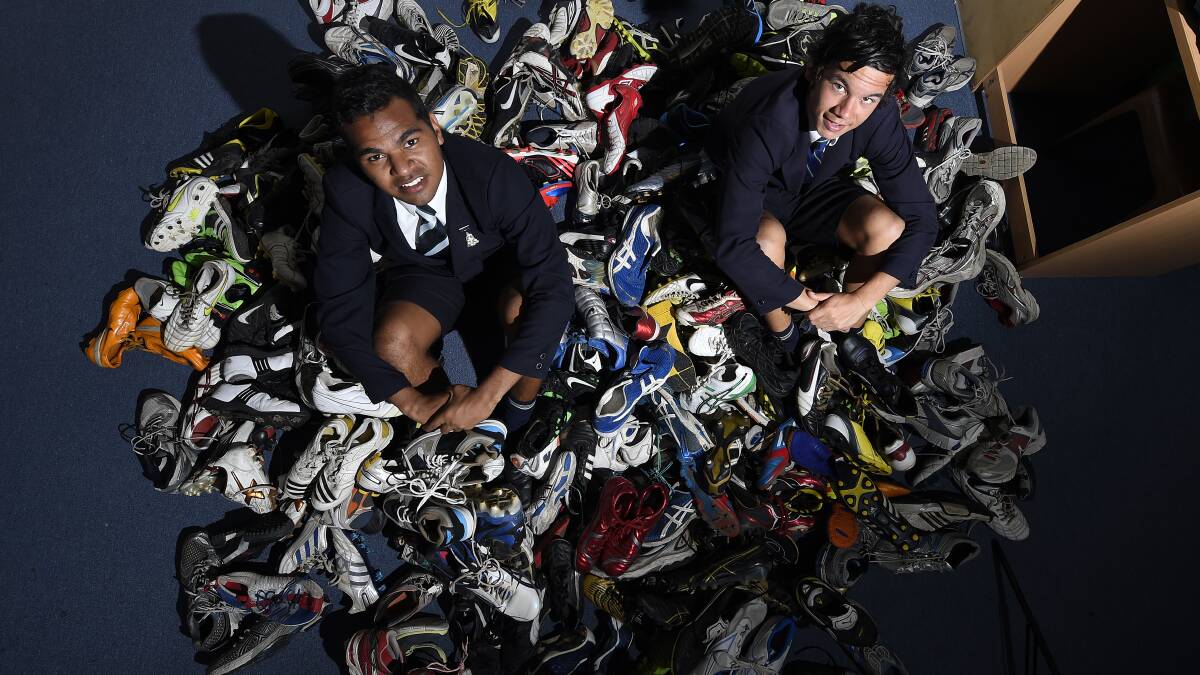 ON THE ROAD: Shane McAuliffe, Daniel Rioli and some of the boots the St Patrick’s College students have donated. PICTURE: JUSTIN WHITELOCK
