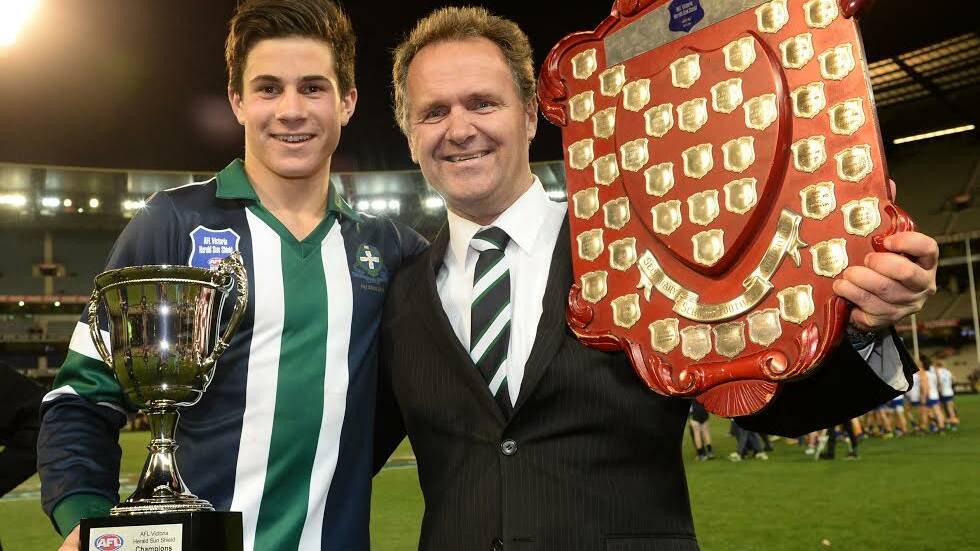 No. 11 pick Liam Duggan with St Patrick's College coach Howard Clark and the Herald Sun Shield trophies at the MCG this year.