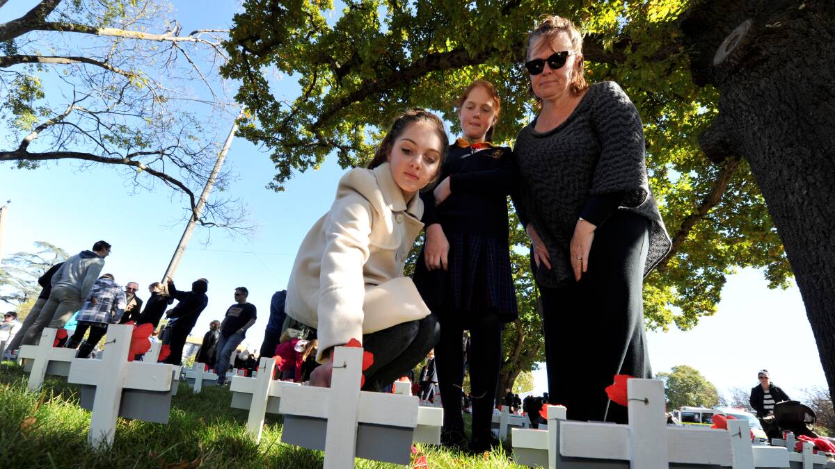 Claire, Katherine and Bev Baxter lay a poppy on the girls' gt grandfather's cross. PICTURE: JEREMY BANNISTER