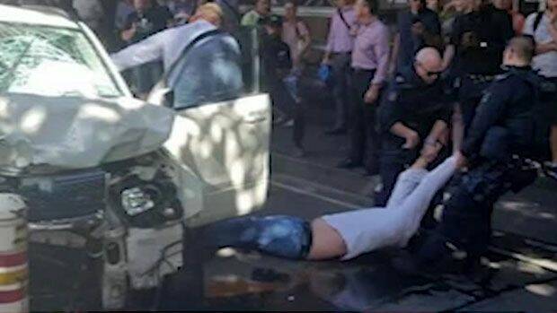 A man is dragged from a car in Flinders Street after an attack that left 18 people injured.  Photo: Seven News