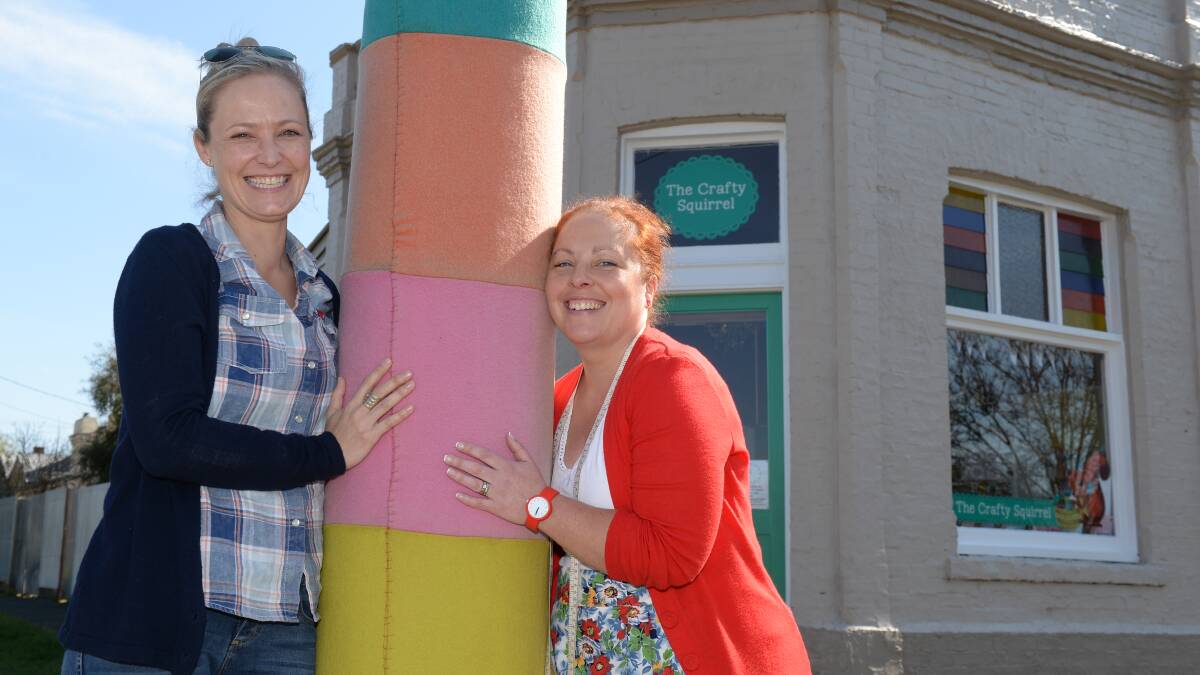Crafty Squirrel owner Morgan Wills, right, has been told by the council to remove her woollen art from a pole outside her store. She is standing by the yarn with fellow supporter Emma Jansen. PICTURE: KATE HEALY