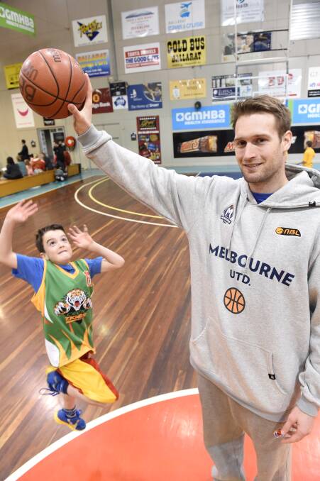 Melbourne United player Mark Worthington holds the ball aloft at a kids’ clinic yesterday at the Minderdome as Lachlan McPhan, 7, soars to reach it. PICTURE: LACHLAN BENCE
