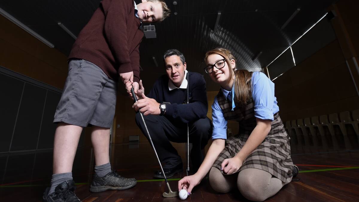 Victorian Teaching Professional of the Year winner Tony Collier (centre) lending a hand to St Thomas More Primary School pupils Josh Clark (left) and Natalia Ripani (right). 