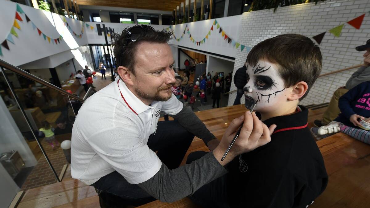 Ballarat Community Health project manager Jim Rodgers paints Rawdon Rodgers’ face at the open day.