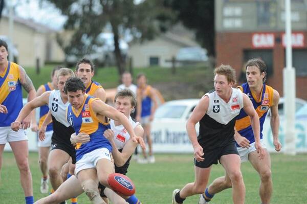 BRING HIM DOWN: North Ballarat first-gamer Tom McDonald does his best to halt Williamstown opponent Tom German. Nick Couch oversees the tussle. Picture: Zhenshi van der Klooster