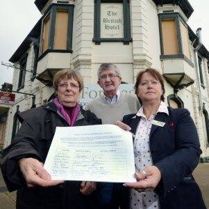 Business and Tourism Creswick members Margaret Giles and Larry Monk hand over a petition to Hepburn Shire Councillor Janine Booth. It calls for the council to urge the owners of The British Hotel, which is falling into disrepair, to restore the historic pub.
