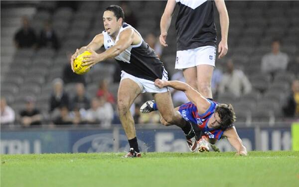 Brett Goodes boots the ball forward despite his oppenent's attempt to foil.