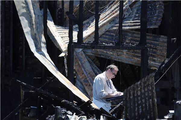 A fire investigator inspects the blackened ruins of the home in Queen St, Sebastopol, after Saturday night's incident.