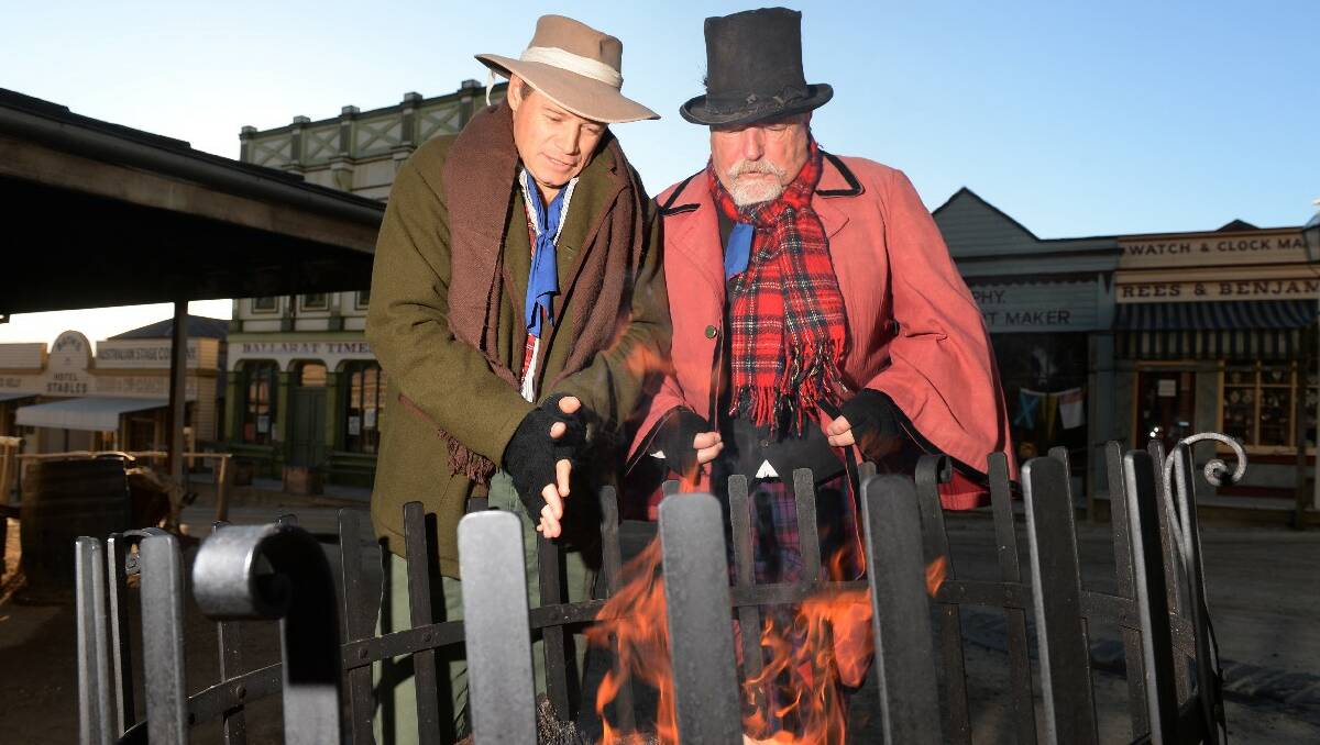Mark Filmer and Ian Burton keeping warm by a fire at Sovereign Hill.