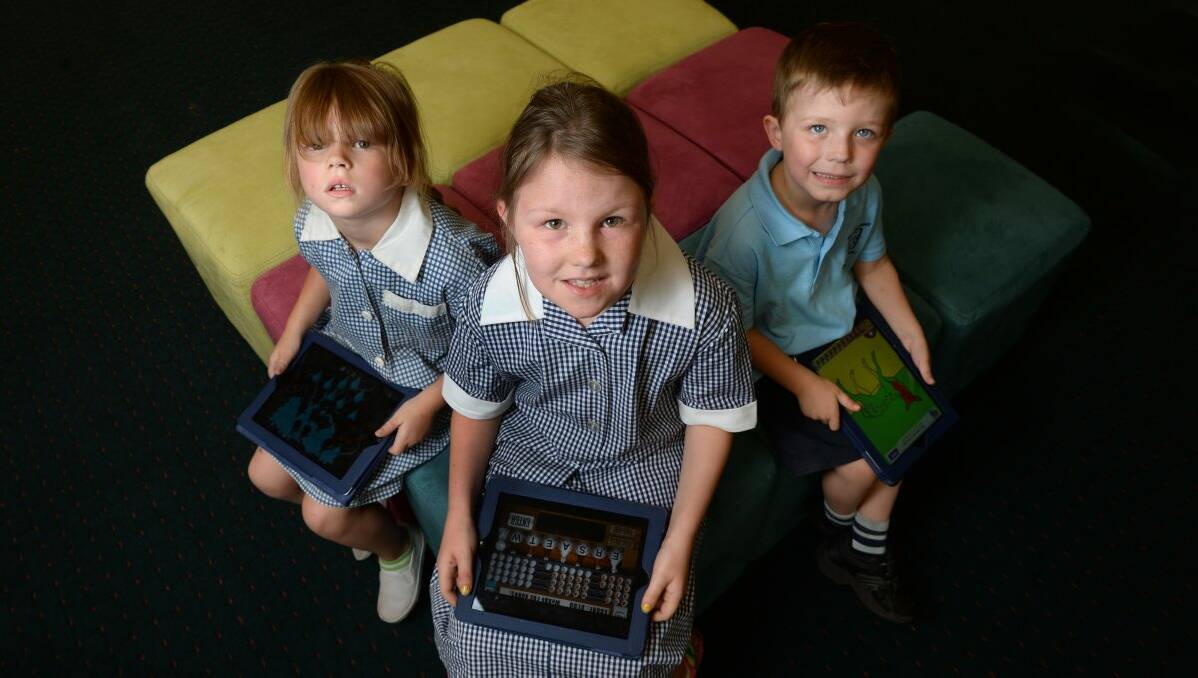 LEARNING: Tahleisha Walsh, 5, Penny Jones, 9, and Liam Jones, 5, with their school iPads. PICTURE: ADAM TRAFFORD