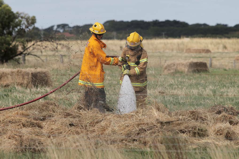 Warrnambool CFA officers finish off extinguishing a fire in a hay field, as local police investigate the circumstances. Picture: ROB GUNSTONE