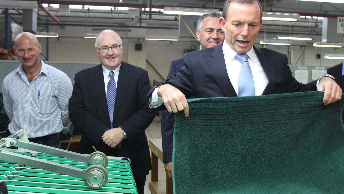 Opposition leader Tony Abbott tries his hand at processing while on tour at the Australian Weaving Mills in Devonport on Thursday. Pic: Katrina Dodd