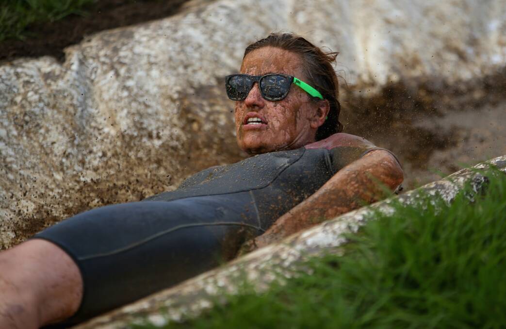 People enjoy the muddy thrills and spills on a waterslide dug into a hillside in Waimauku, New Zealand. Photo: Getty Images