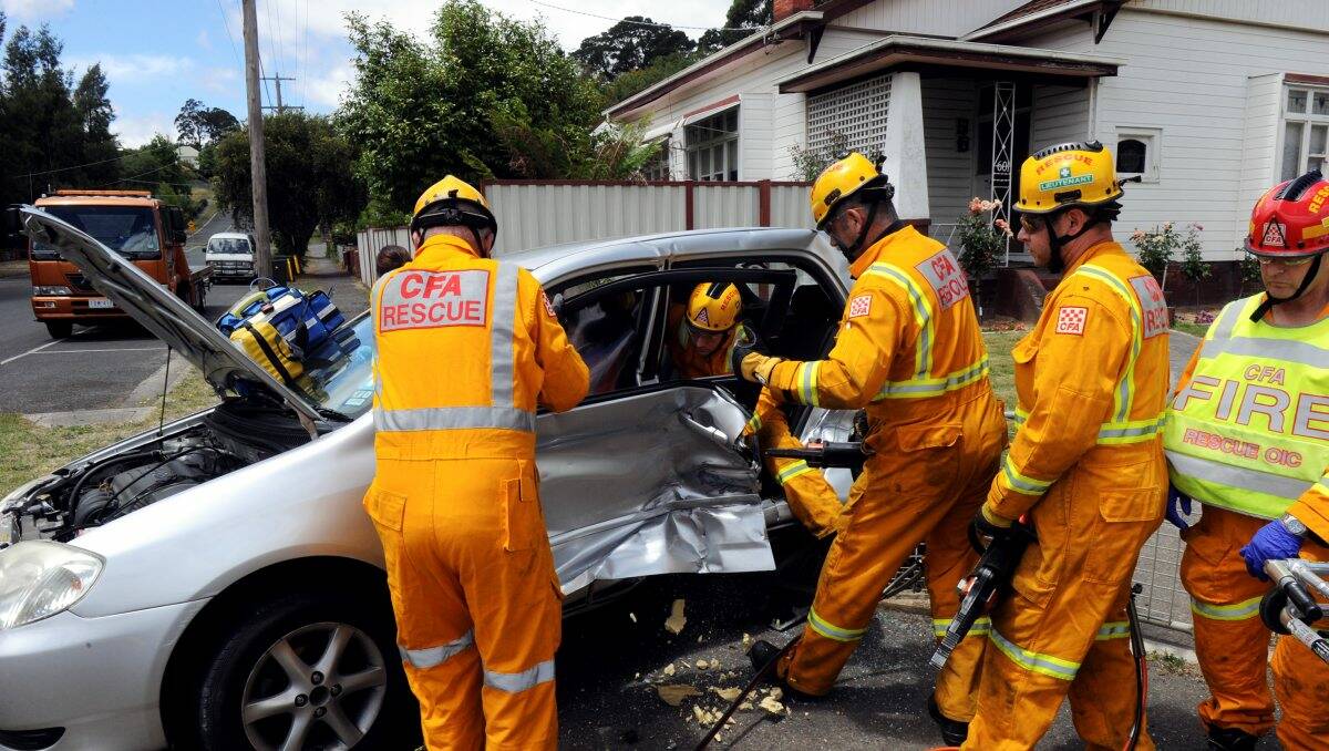  Firefighters help paramedics after cutting free one of two passengers from a car involved in a two-car collision on the corner of Barkly and Bradshaw Streets, Golden Point, yesterday. PICTURE: JEREMY BANNISTER