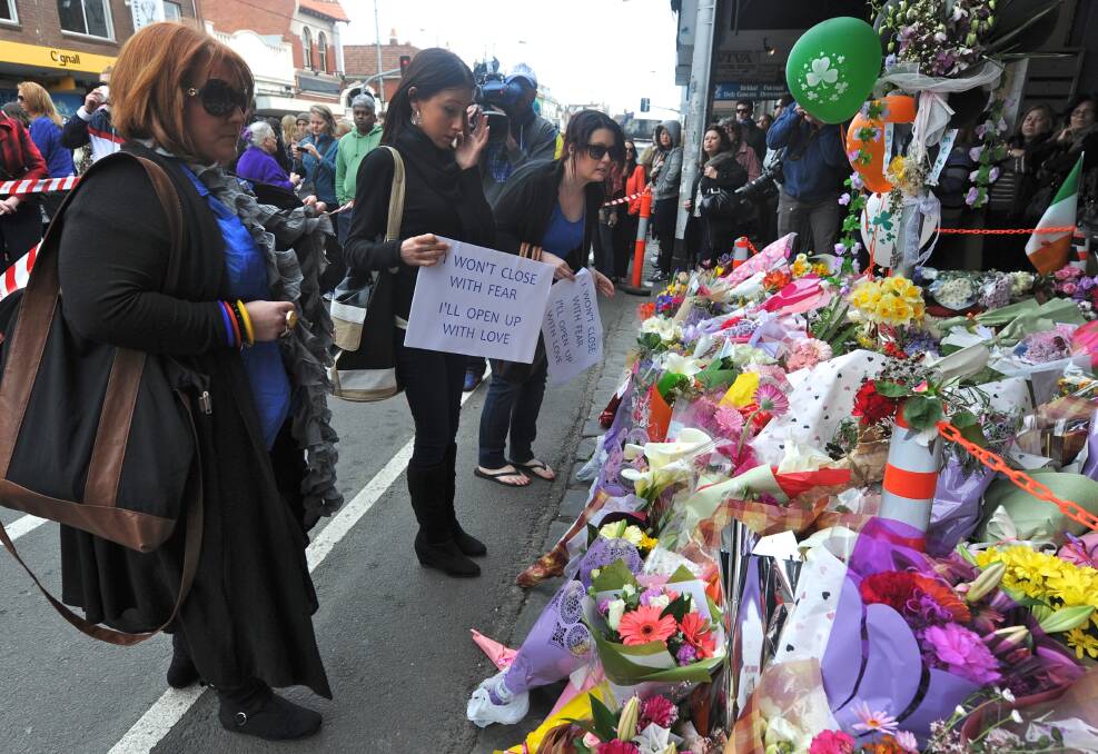 Participants in last weekend’s march for Jill Meagher inspect some of the floral tributes left in her honour.