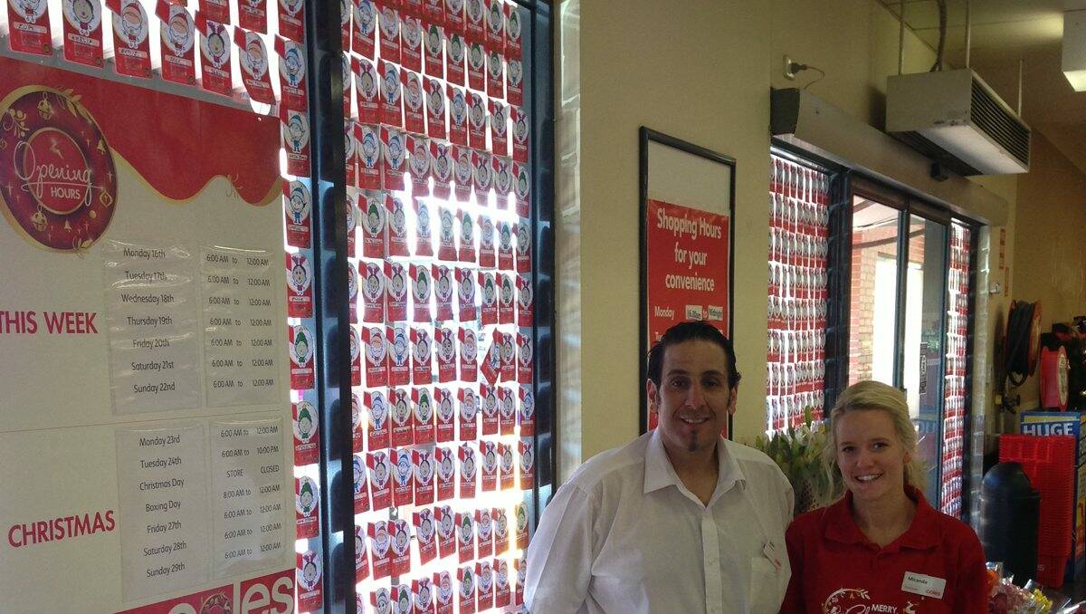 Coles Victoria Street store manager John Martino and Miranda Brennan beside a wall of Coles Red Kite cards.