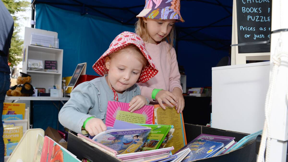 Buninyong's Violet Weyers, 4, and Sanna Weyers, 7, trawl through a collection of books at the Clunes Book Town Festival. Picture by Kate Healy