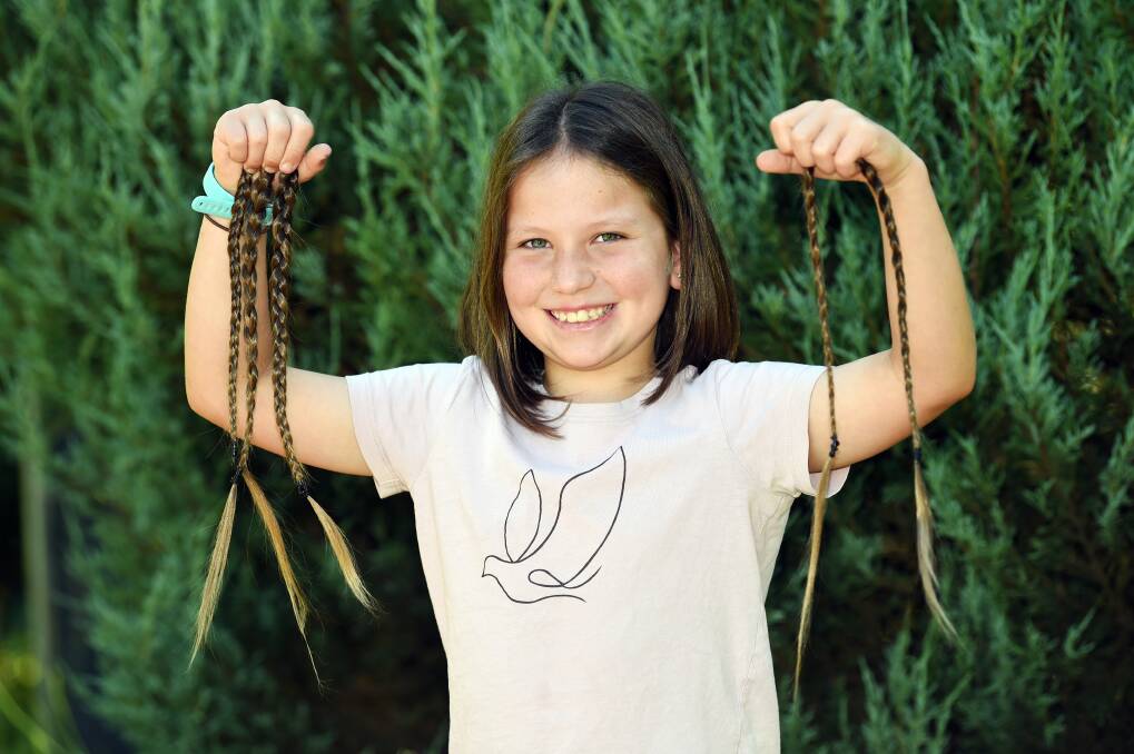 Sophie Grech, 10, holding plaits of hair from her head, which will be donated to make wigs for people with cancer. Picture by Kate Healy