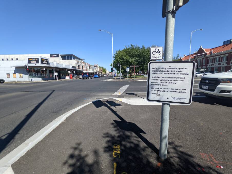 A sign directing pedestrians and cyclists to use existing crossings to continue on the shared path.