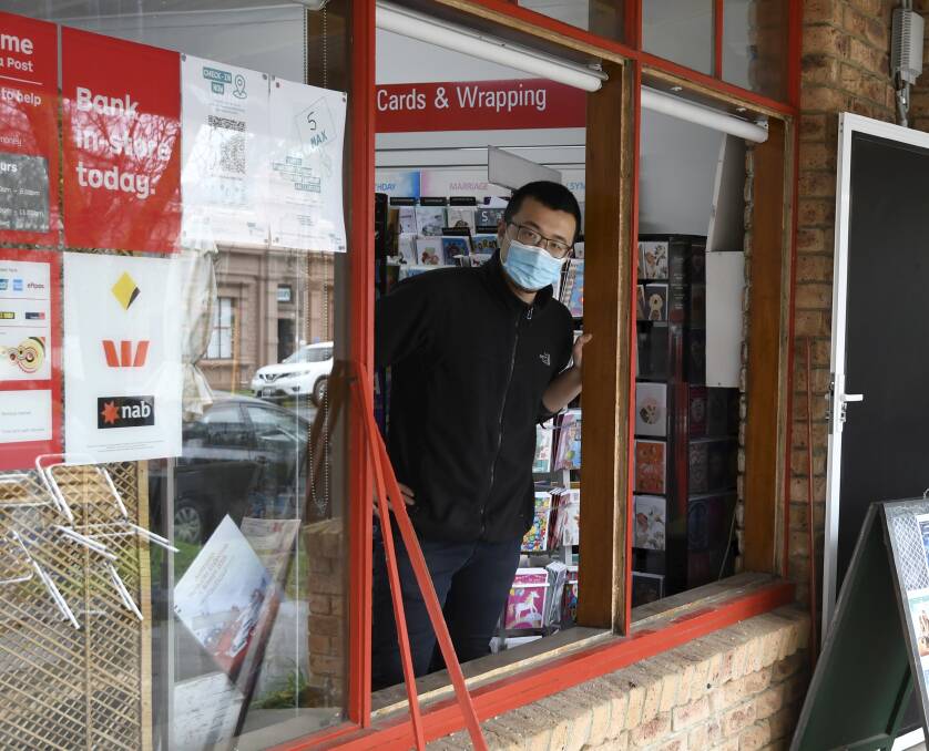 Buninyong Post Office owner Yao Zhao looking through his broken shop window.