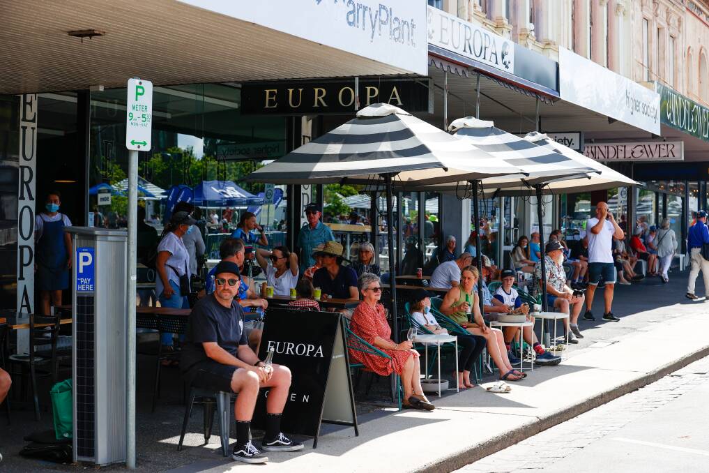 Cycling fans watching all the action while enjoying a coffee outside the Europa Cafe.