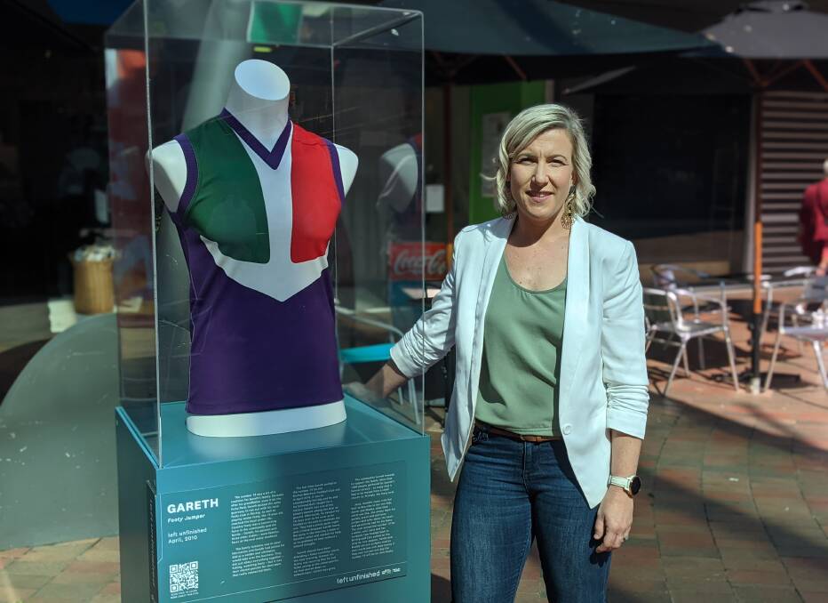 REMINDER: Josie Postlethwaite with her brother Gareth Cozens' football jumper on display at Bridge Mall. Picture: Jackson Russell
