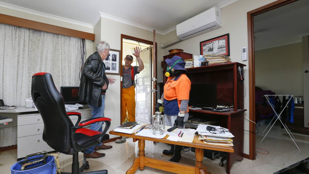 HE WON'T BACK DOWN: Russell Castley, with emergency workers, in his flood-damaged unit. Pictures: Luke Hemer.
