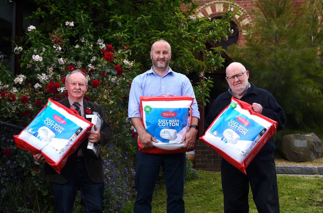 DOONAS DOING GOOD: UnitingCare's Warwick Davison receives doonas and bedding from Ron Fleming and Len Tyzack from Buninyong Freemasons Lodge. Picture: Adam Trafford.