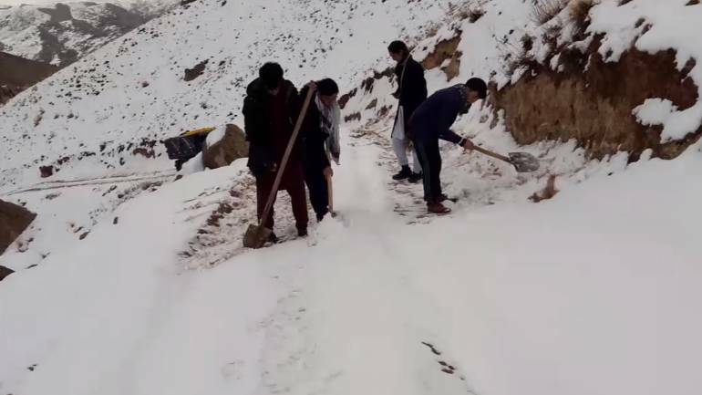 Volunteers shovel snow from the mountain tops to smuggle in aid to starving Afghan families. Photo: supplied