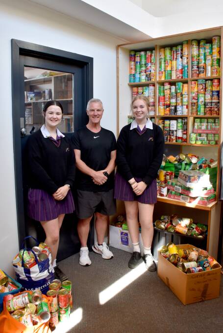 Phoenix P-12 Community College students Bree Price and Ashley Stevens with Soup Bus director Craig Schepis and some of the 2500 cans of food students collected to donate to Soup Bus. Picture supplied