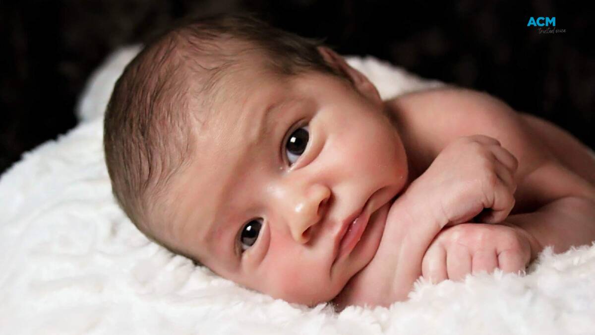 A newborn baby lying on a plush blanket looks into the camera. File picture.