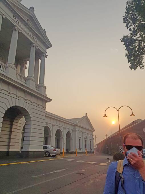 A commuter shielding his face from the smoke at Ballarat Railway Station this morning. Photo: Sophie Ellis via Twitter.