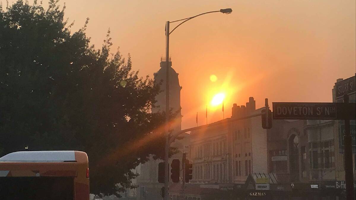 The sun rising in the hazy sky behind Ballarat Town Hall on Tuesday morning.